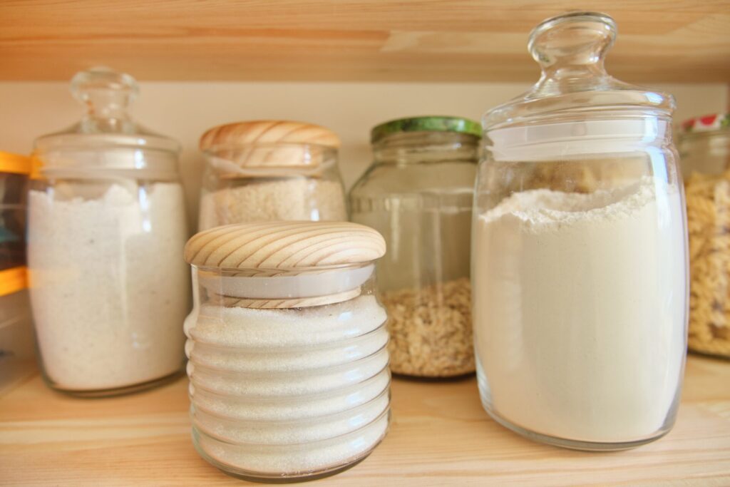 Die richtige Lagerung von Mehl erhöht die Haltbarkeit. Mehl im Schrank in verschiedenen Gläsern.