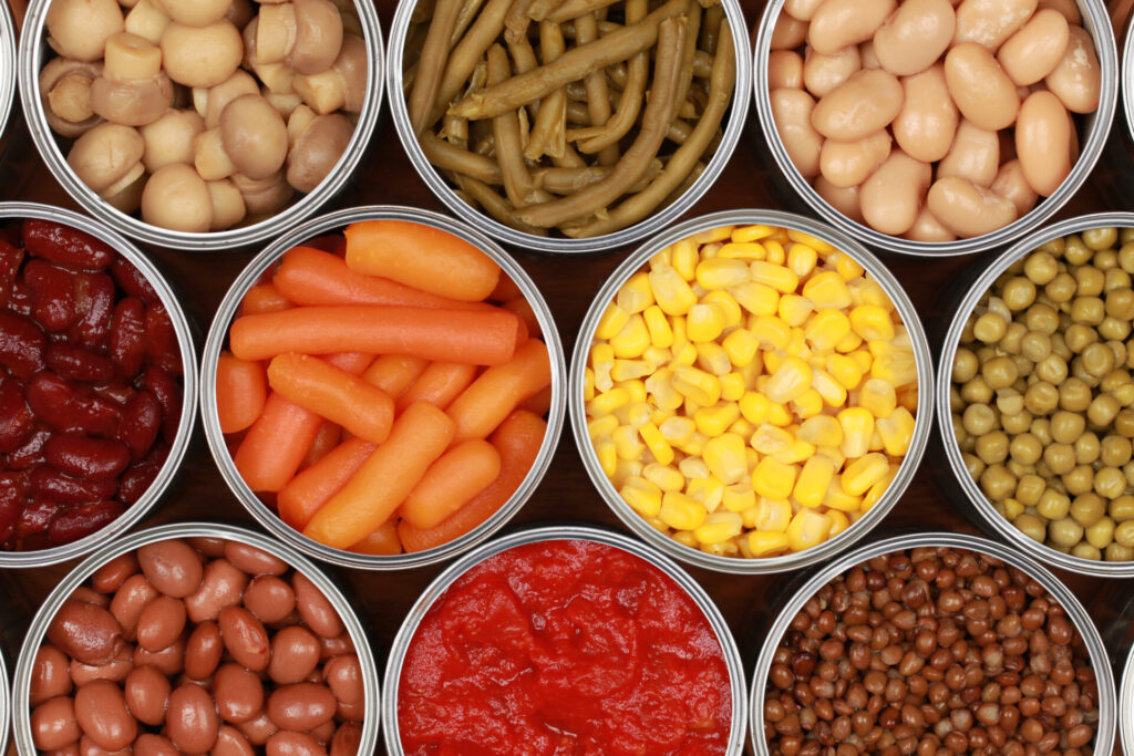 Gekochtes Gemüse in Konserven eignet sich ideal für die Vorratshaltung. von oben fotografiert, man sieht Mais, Bohnen, Tomatensoße und Mören.