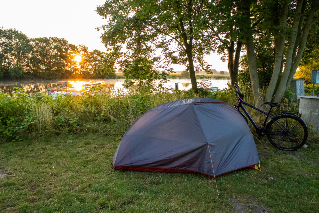 Sonnenaufgang über der Weser mit Zelt und Rad