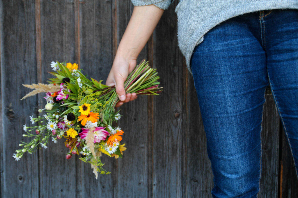 Jeans mit Frau hält Blumenkranz in der Hand