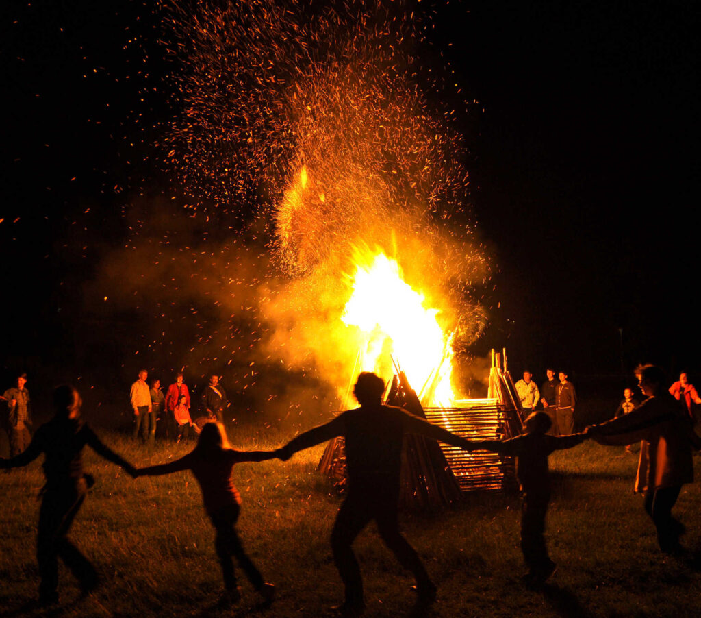 Sommersonnenwende  Menschen tanzen um ein großes Feuer