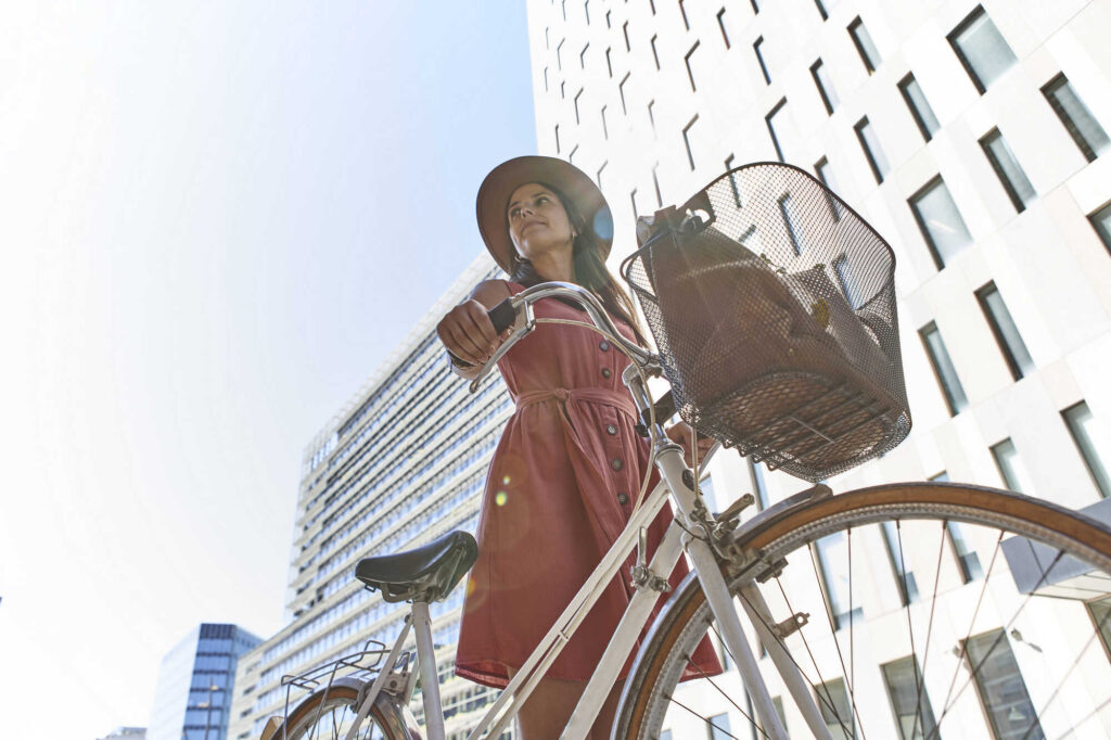 Natürlicher Sonnenschutz: Eine Frau mit Sonnenhut schiebt ihr Fahrrad